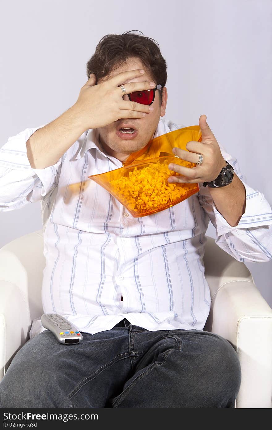 A young man watching a movie in 3D, with stylish 3D glasses and eating popcorn. A young man watching a movie in 3D, with stylish 3D glasses and eating popcorn.