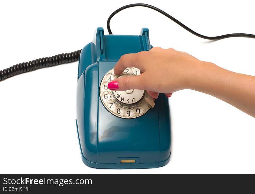 Ladies hand dials the number on the old phone isolated on a white background. Ladies hand dials the number on the old phone isolated on a white background.