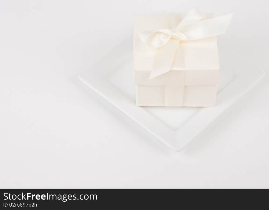 Small cream colored favor box on white plate and background. Small cream colored favor box on white plate and background