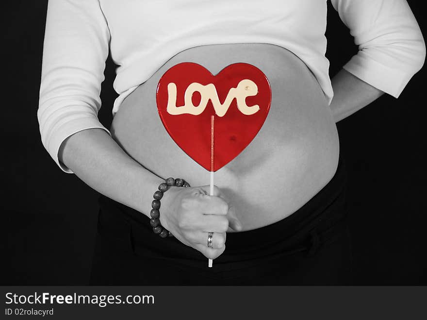 Pregnant woman keeping the red lillipop with the love inscription