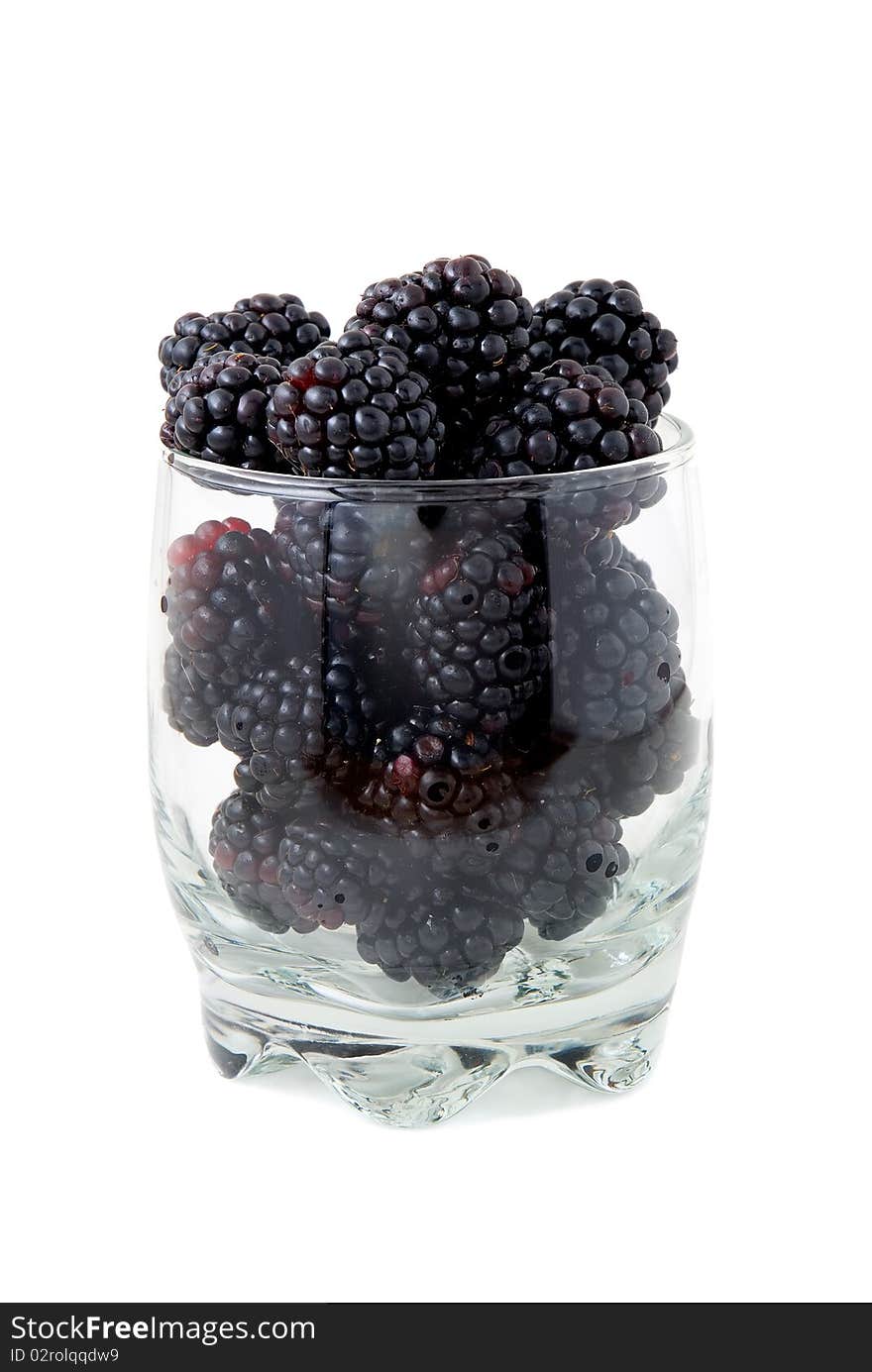 Blackberries in a glass are photographed on a white background