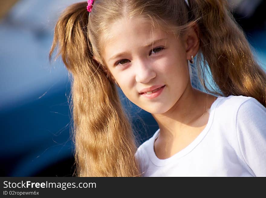 Portrait of little girl with long hair,smiling at the camera the blue