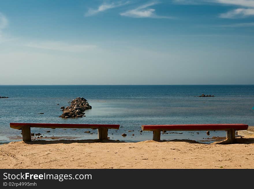 Two empty benches on the beach.