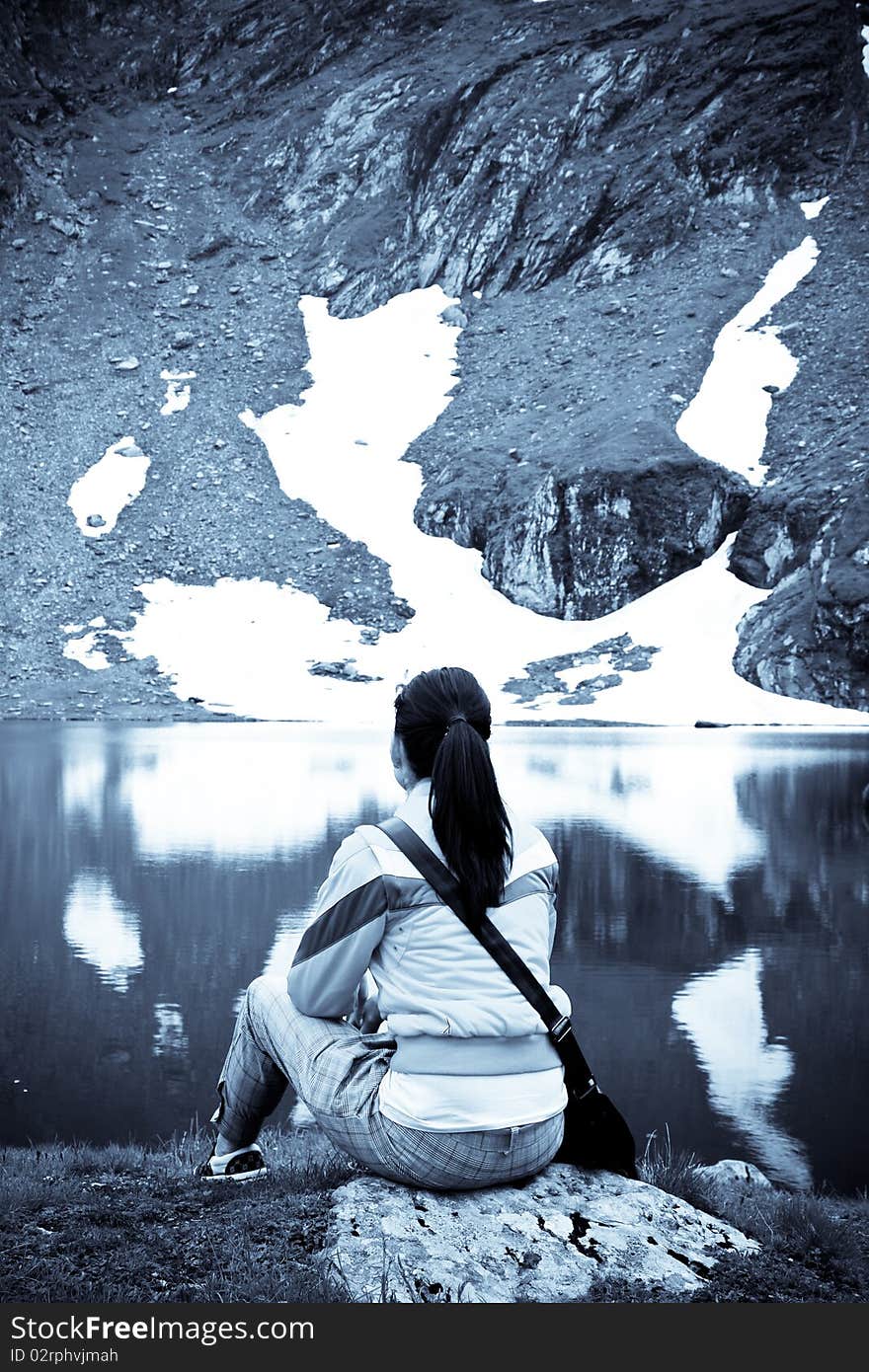 Woman sitting on a rock in a beautiful mountain scenery. Woman sitting on a rock in a beautiful mountain scenery