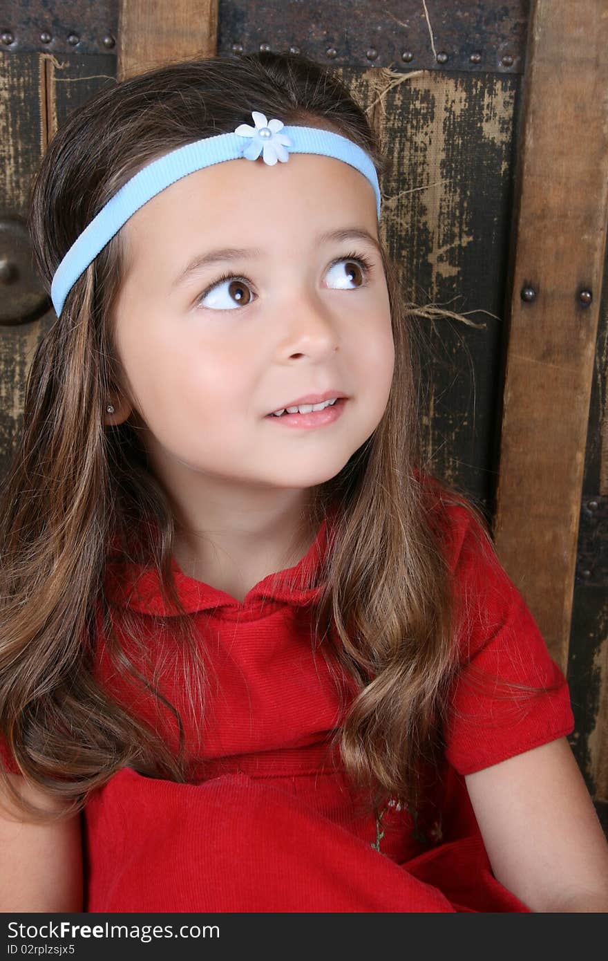 Cute brunette girl sitting against an antique trunk wearing a headband. Cute brunette girl sitting against an antique trunk wearing a headband