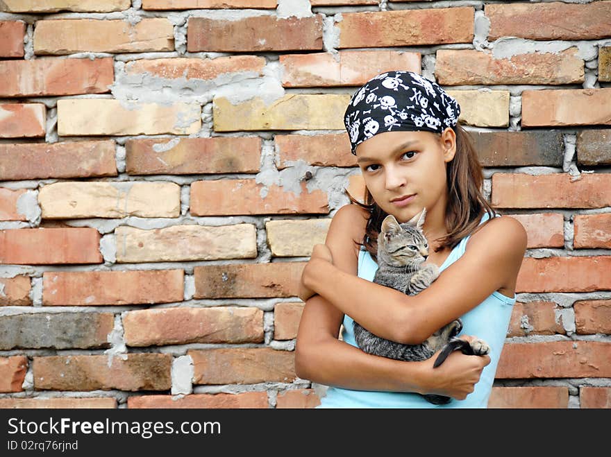 Teenage girl outdoor portrait with cat in arms over brick wall. Teenage girl outdoor portrait with cat in arms over brick wall