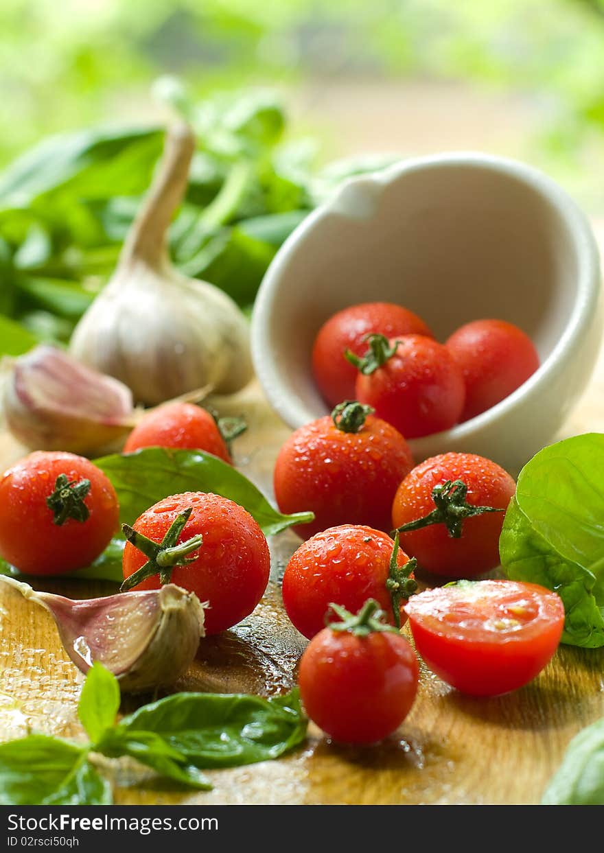 Cherry tomatoes on table and in a bowl with basil and garlic