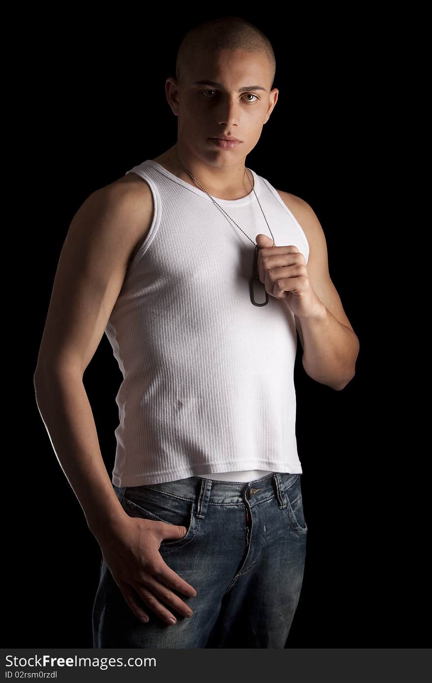 A good looking, muscular built, man on a black background with dog tags. A good looking, muscular built, man on a black background with dog tags.