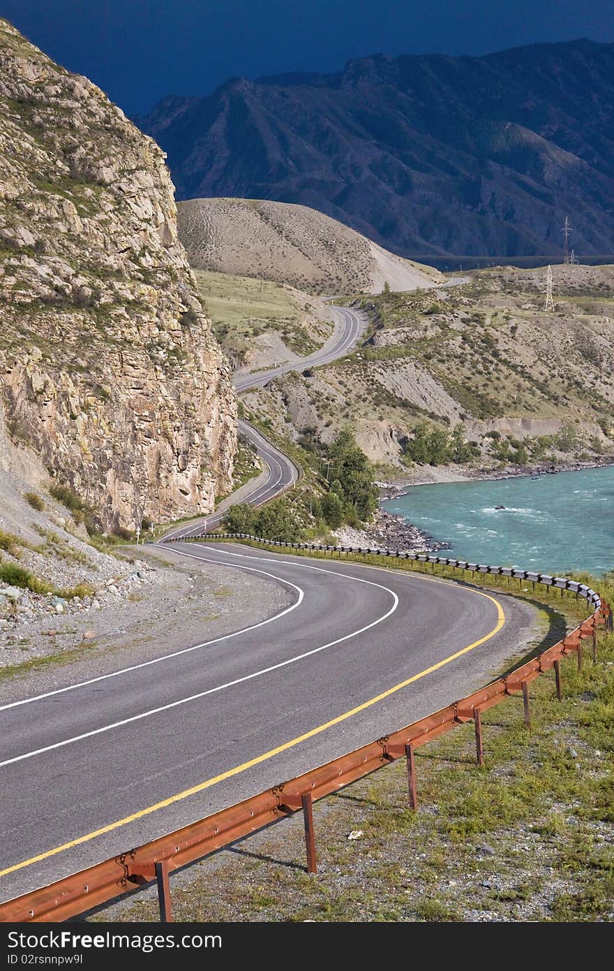 The road to mountains does abrupt turn before breakage at the rough river. The road to mountains does abrupt turn before breakage at the rough river