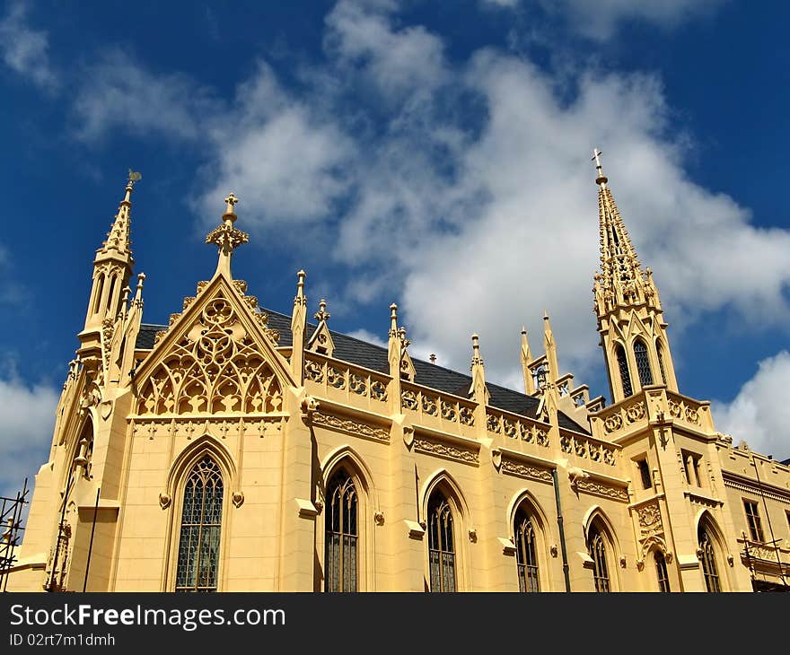 Yellow colored neo-gothic church with spires under blue sky, Lednice, Czech republic