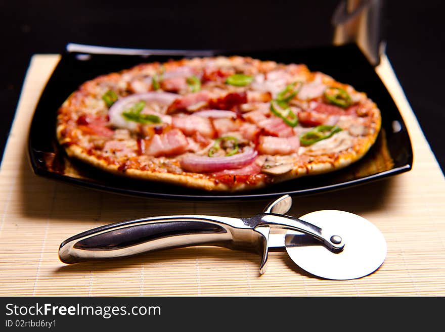 Delicious pizza with everything on it and pizza cutter in focus