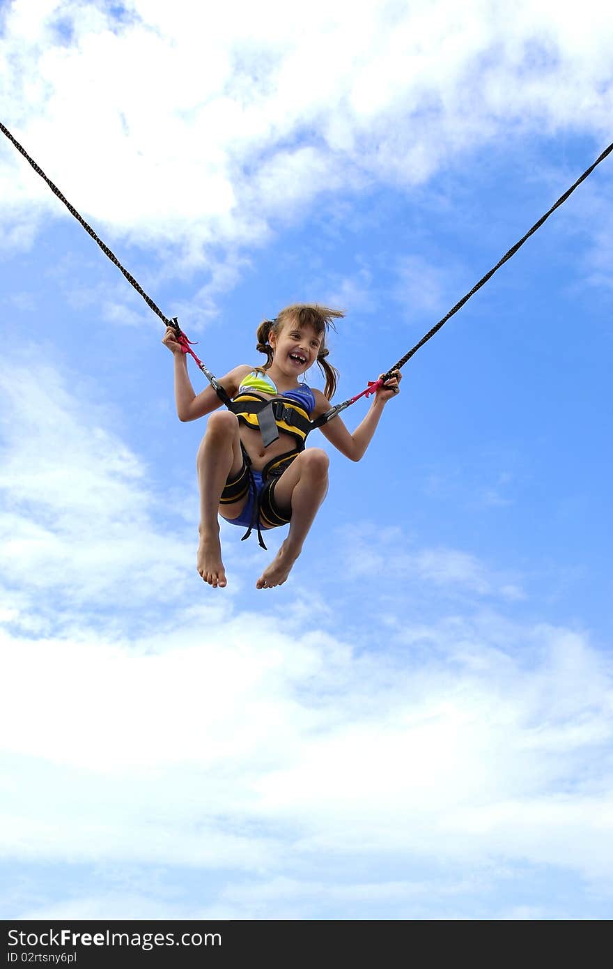 Girl jumping on ropes relating to the blue sky. Girl jumping on ropes relating to the blue sky