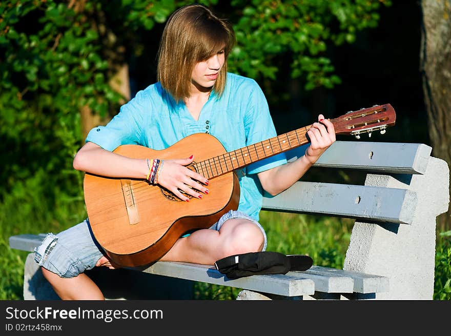 Beautiful teenage girl with guitar in the green park