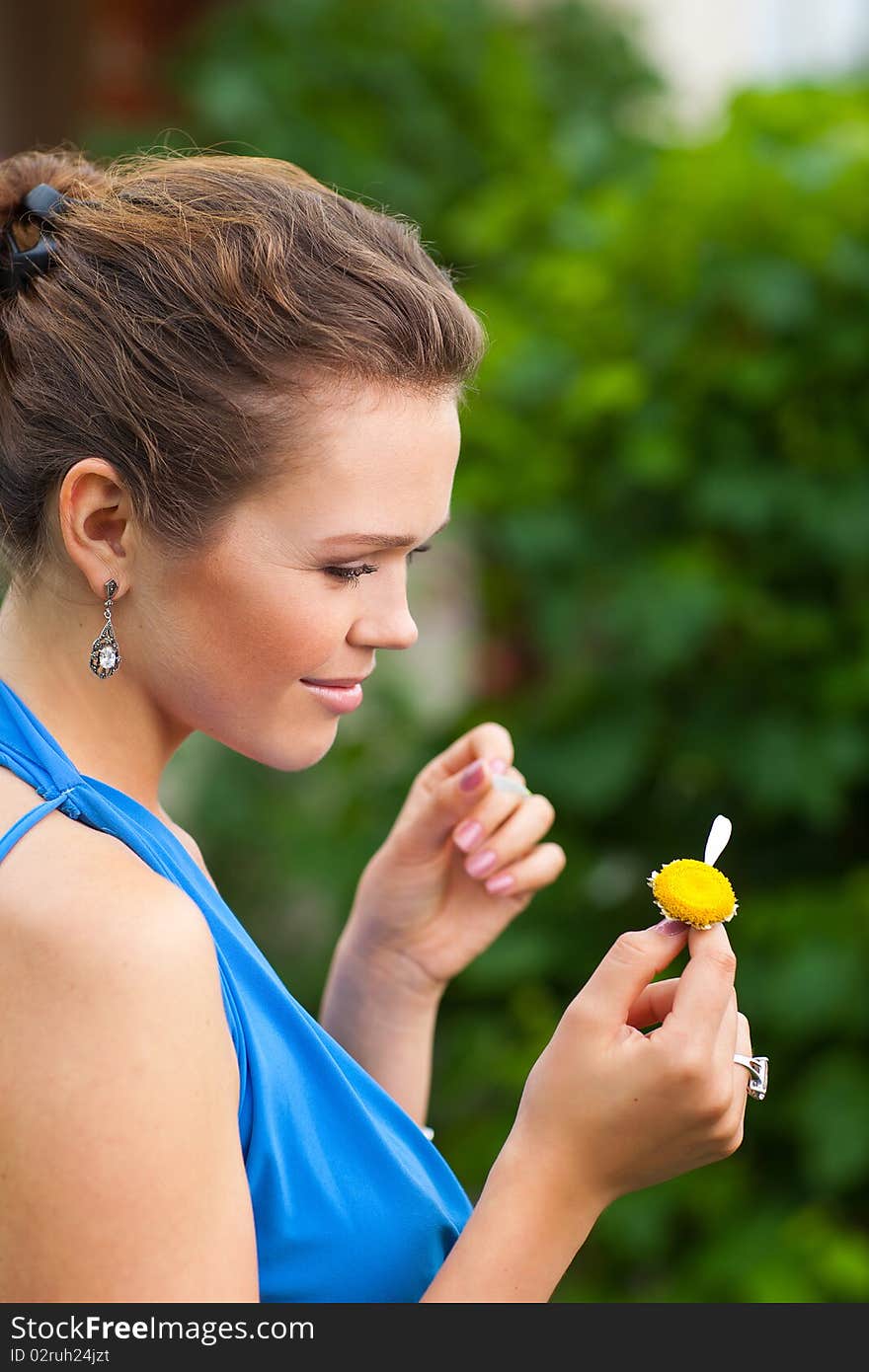 Attractive young adult holding camomile and tearing off petals. Attractive young adult holding camomile and tearing off petals