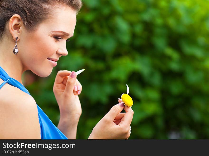 Attractive young adult holding camomile and tearing off petals. Attractive young adult holding camomile and tearing off petals