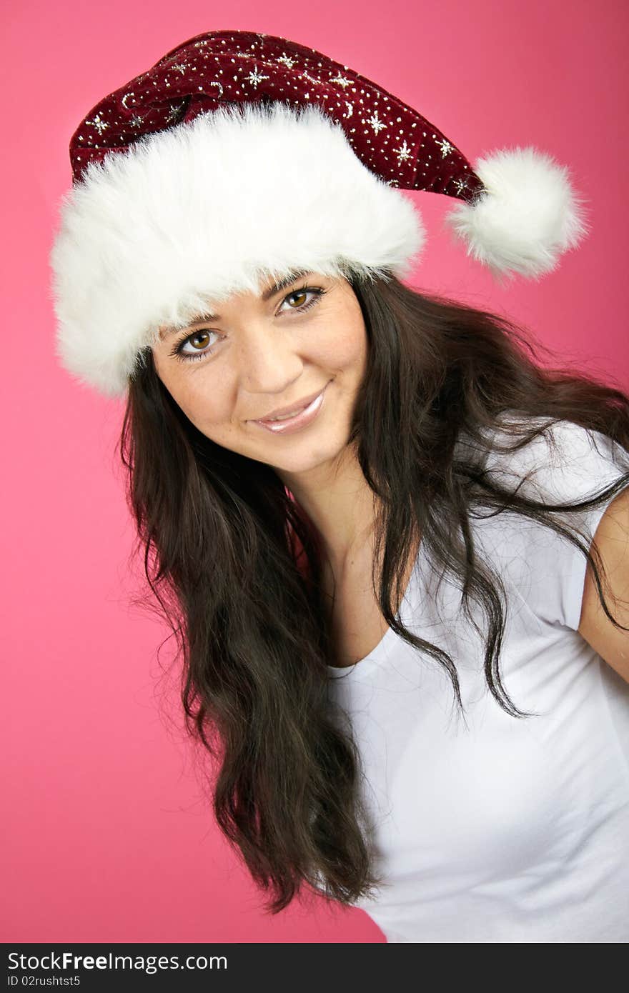 Winter portrait of a smiling christmas woman in front of a pink background