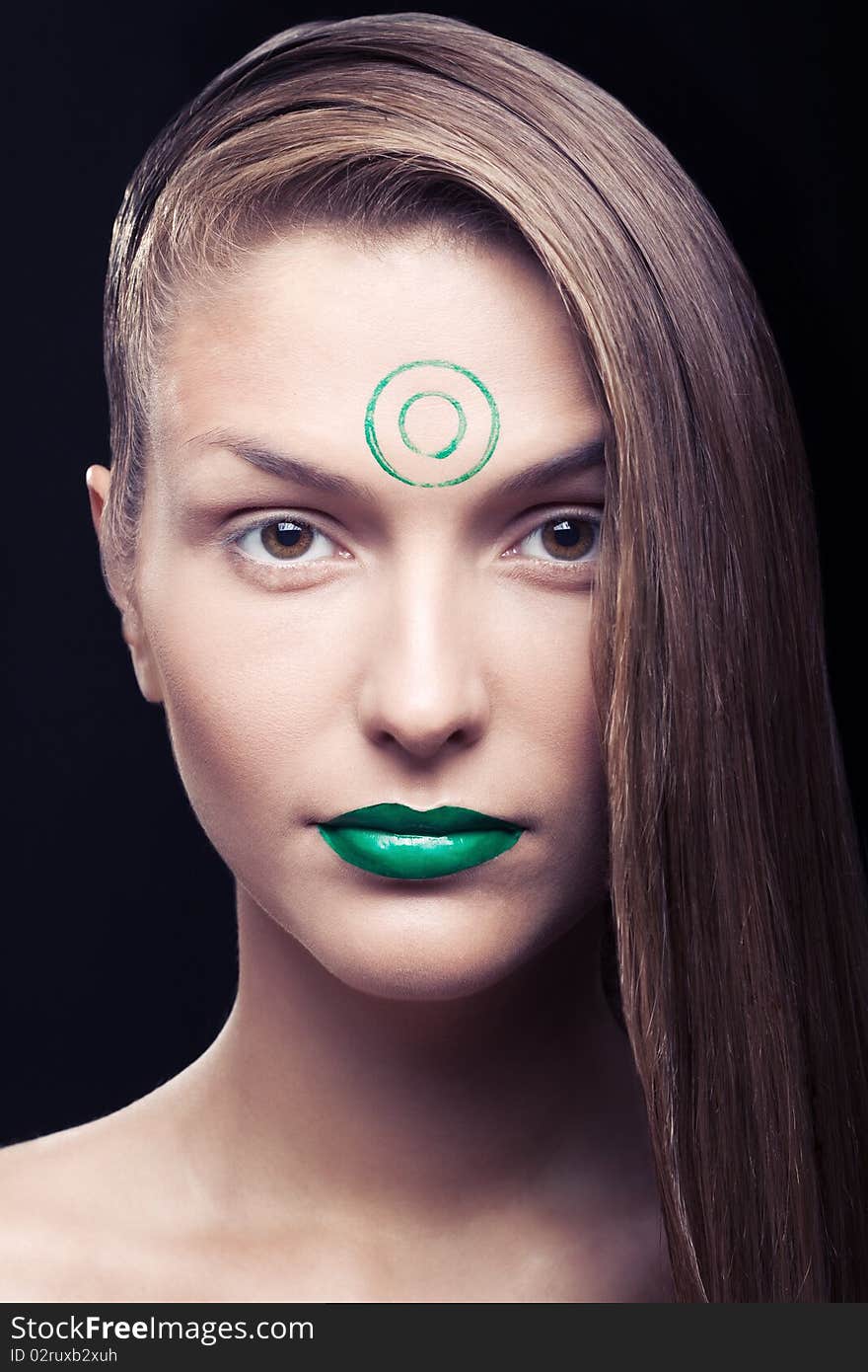 Art make-up on the person young, beautiful, girls. The girl with a make-up of green lips and green circles on a forehead