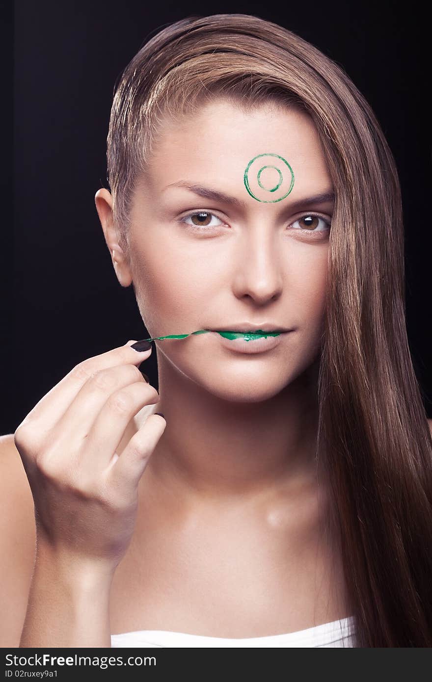 Art make-up on the person young, beautiful, girls. The girl with a make-up of green lips and green circles on a forehead