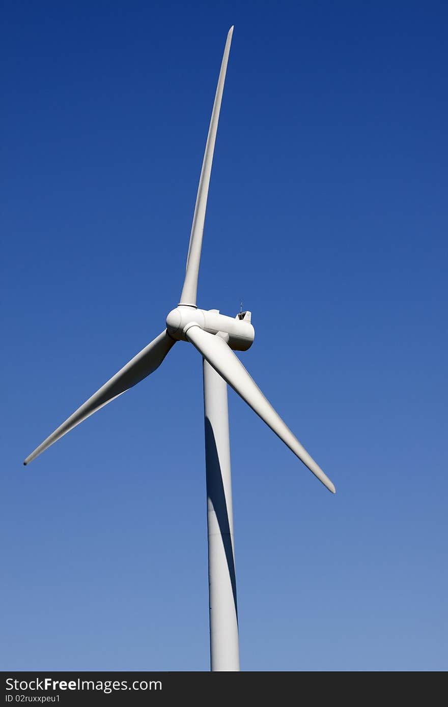 The white wind turbine generating electricity on blue sky. The white wind turbine generating electricity on blue sky