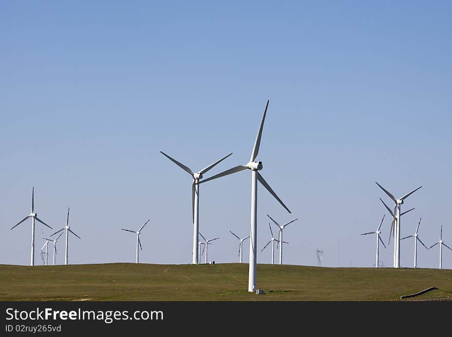 The white windmills generating electricity on blue sky