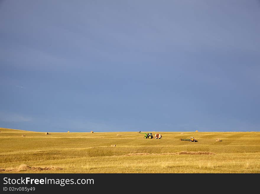 The bundles of grass machine working in summer prairies