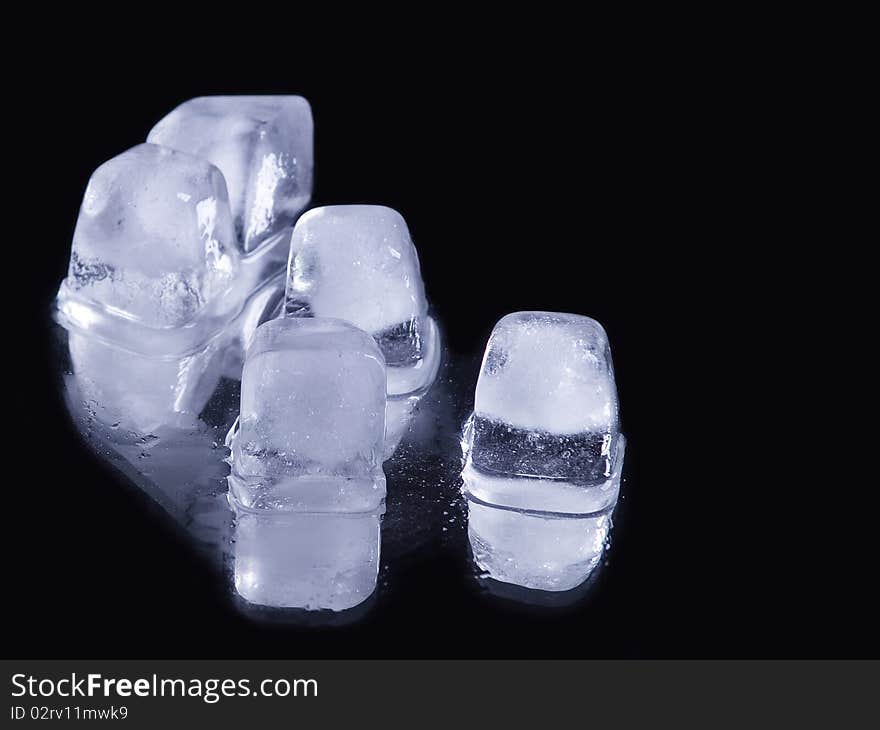 Some ice cubes over reflective black background