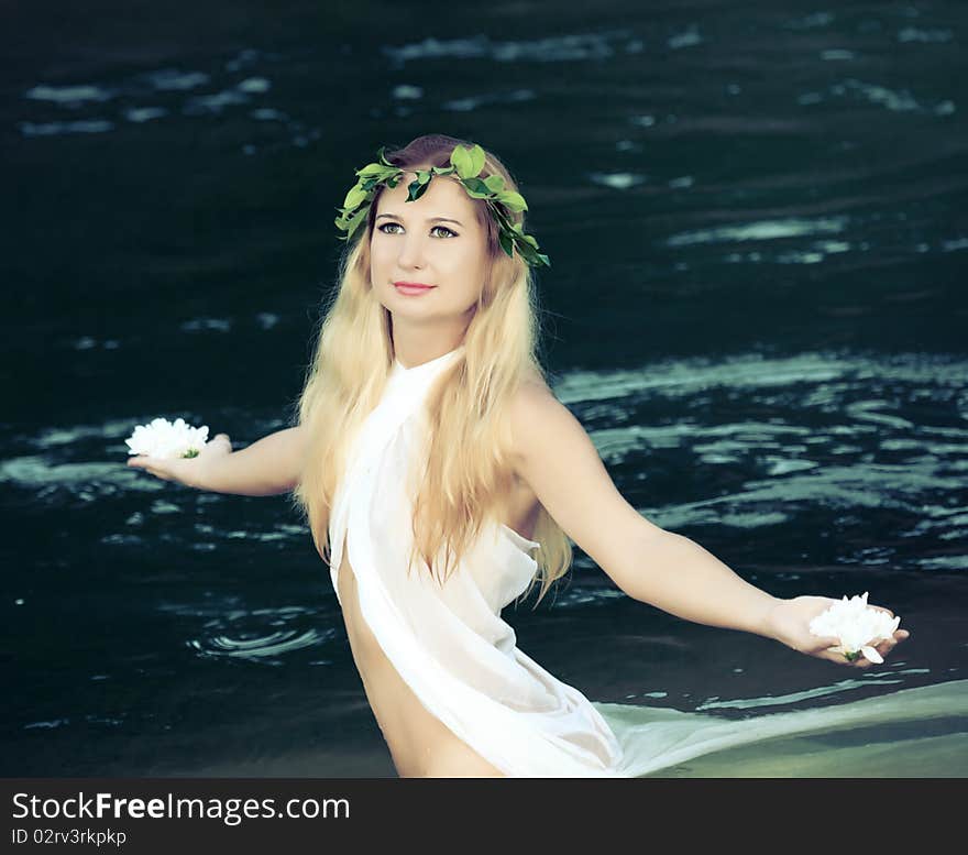 Beautiful woman as a forest nymph on the river