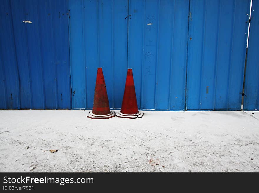 Traffic cone in front of a blue wall