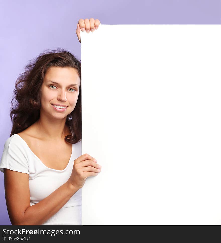 Beautiful brunette holding the edge of a white billboard. Beautiful brunette holding the edge of a white billboard