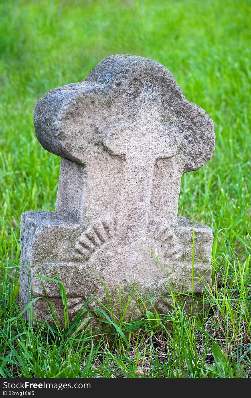 Ancient stone Christian cross on a green grass background. Ancient stone Christian cross on a green grass background