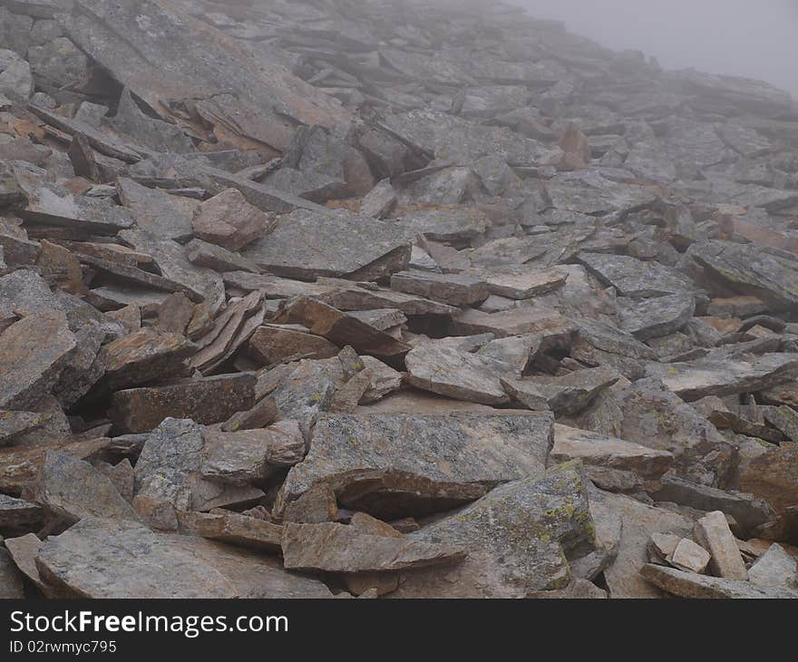 Stony, alpine, tourist trail mountain during bad weather, in fog