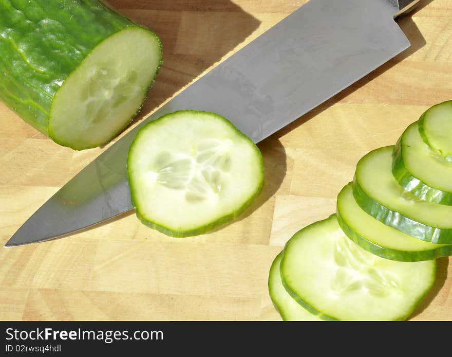 Sliced cucumber with kitchen knife on chopping board