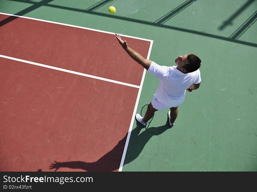 Young man play tennis outdoor on orange tennis field at early morning