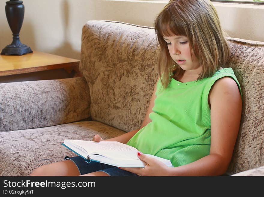 Young girl sitting on the couch reading. Young girl sitting on the couch reading.