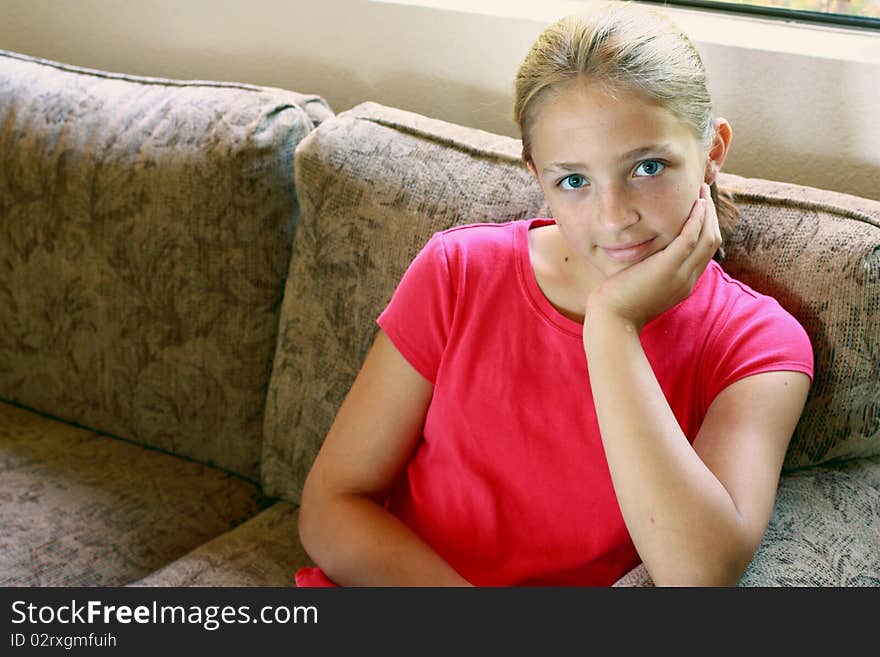 Young girl with red blouce sitting brown couch. Young girl with red blouce sitting brown couch.