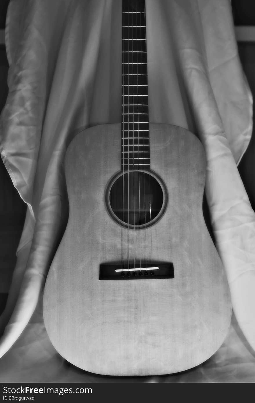 Black and White Acoustic Guitar Against a White Sheet.