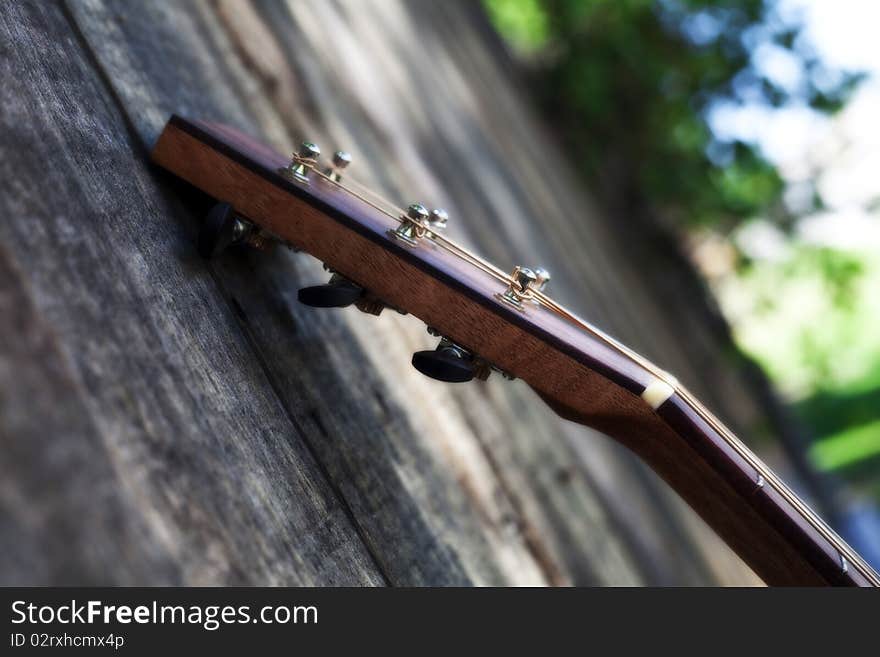 Head of Acoustic Guitar Against a Fence