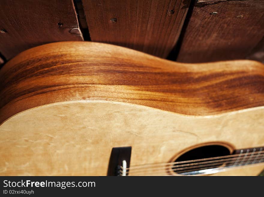 This is a picture of the side of an acoustic guitar against a redwood fence with a long view of the fence. This is a picture of the side of an acoustic guitar against a redwood fence with a long view of the fence..