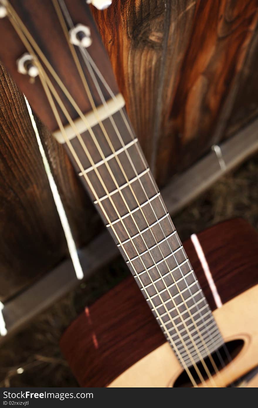 This is an acoustic guitar fret board against a fence.