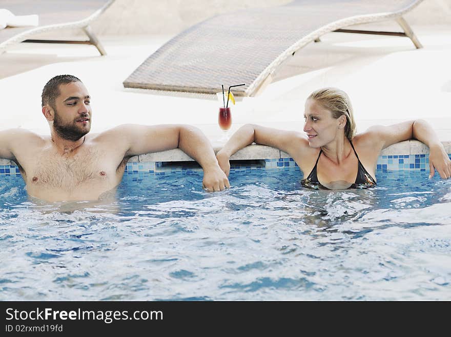 Happy young couple in love have fun relax and drink coctail at indoor wellness swimming pool. Happy young couple in love have fun relax and drink coctail at indoor wellness swimming pool