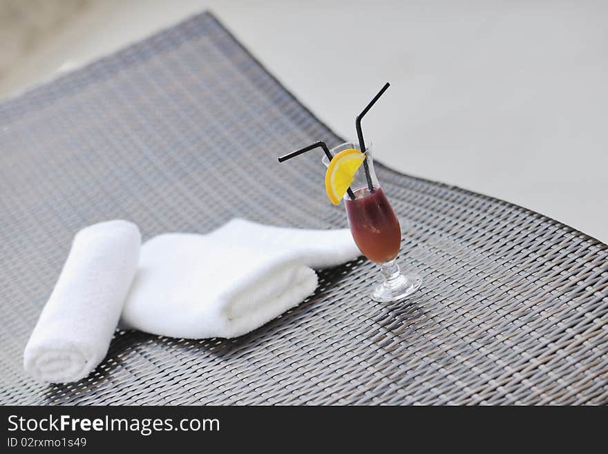 Coctail dring with orange att sunny day on swimming pool side with white towel decoraton. Coctail dring with orange att sunny day on swimming pool side with white towel decoraton