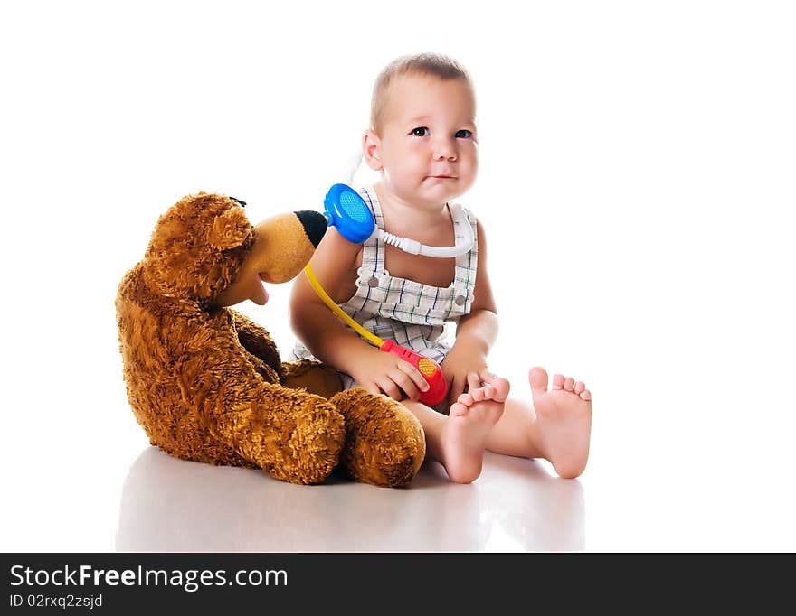 Little boy playing doctor with a teddy bear - studio shot - isolated