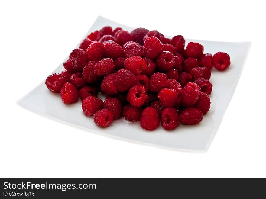 A heap of red raspberries on plate. Isolated on white