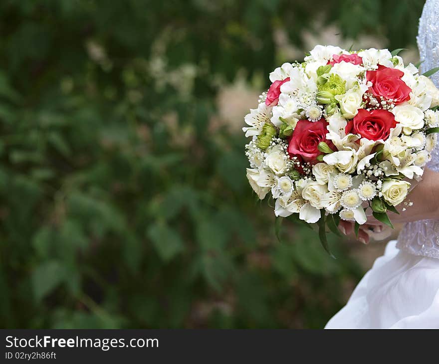 A beautiful frangipani flower wedding bouquet in front of a white wedding dress