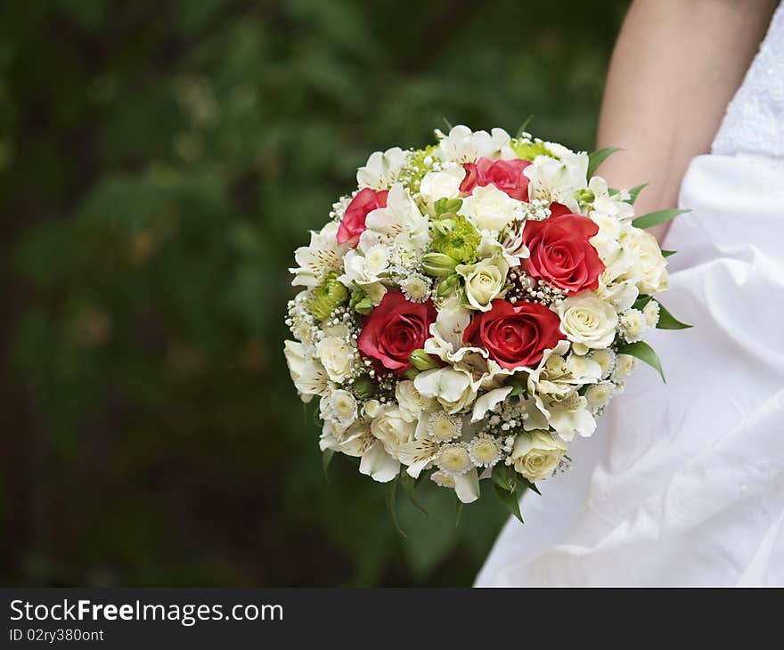 A beautiful frangipani flower wedding bouquet in front of a white wedding dress