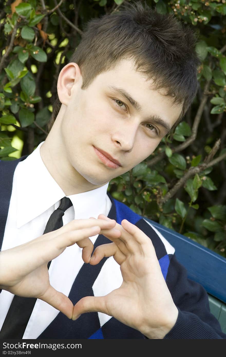 Teen boy in the park making heart shape with hands declaration of love. Teen boy in the park making heart shape with hands declaration of love