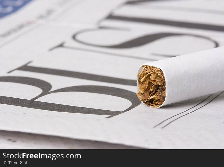 A cigarette laying on top of a newspaper with the word business on it. A cigarette laying on top of a newspaper with the word business on it.