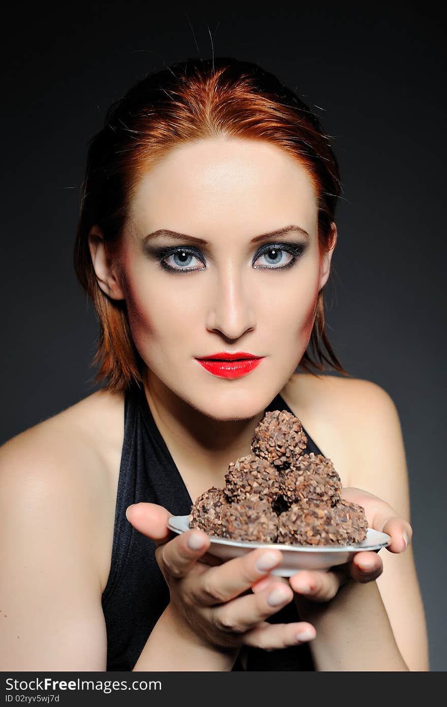 Beautiful retro woman with red lips holding many truffel chocolate sweets. focus on sweets. Beautiful retro woman with red lips holding many truffel chocolate sweets. focus on sweets