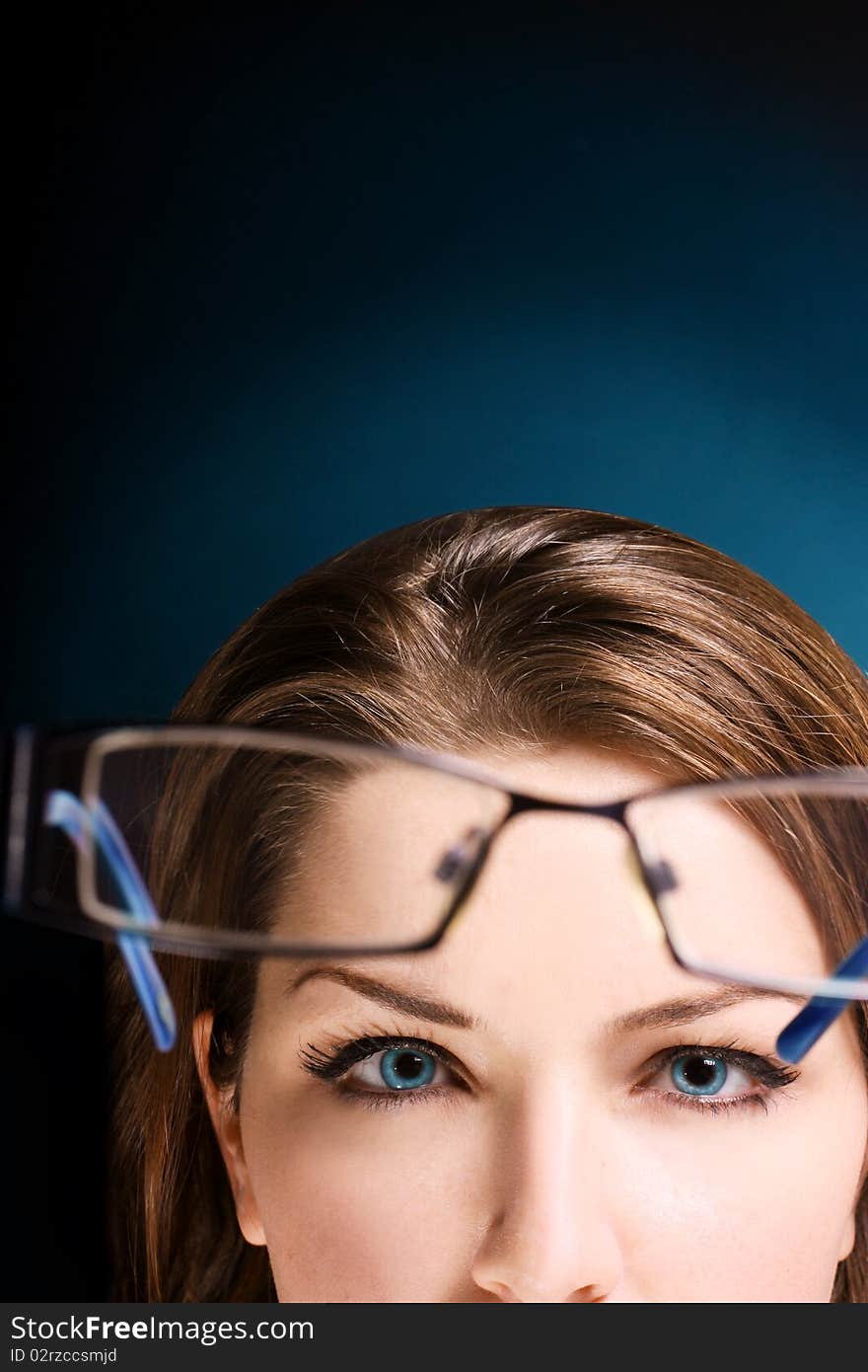 The upper half of a womans face looking at her glasses. Space for text. The upper half of a womans face looking at her glasses. Space for text.