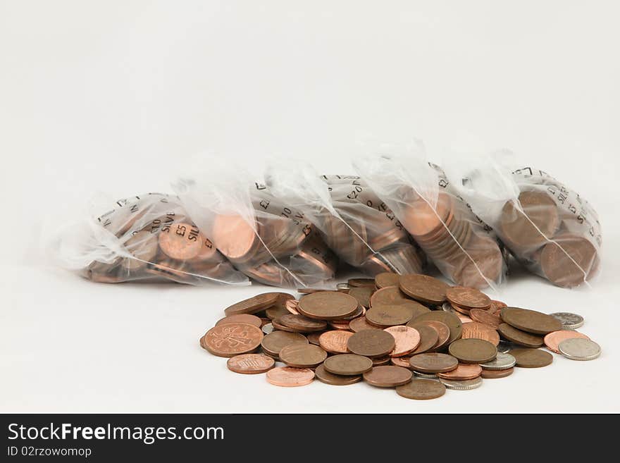 A pile of loose coins with bags of coins in the background isolated on white. A pile of loose coins with bags of coins in the background isolated on white.